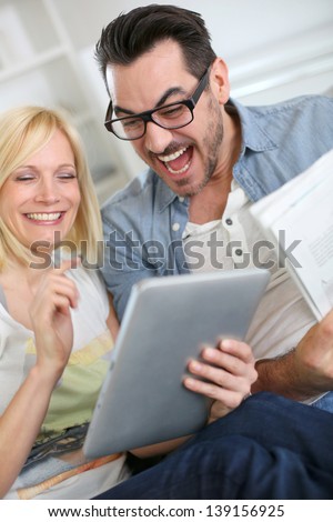 Couple reading news on both internet and paper