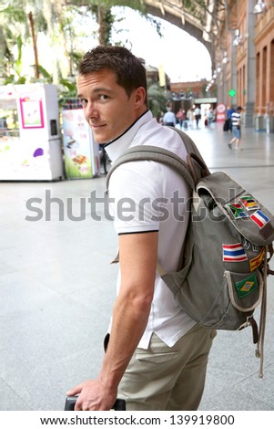 Smiling tourist with backback in train station
