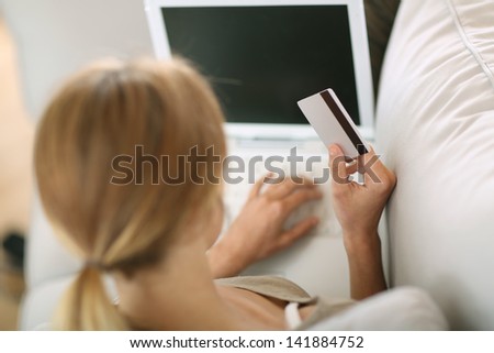 Back view of woman in sofa shopping on internet