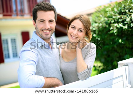 Cheerful Couple Standing In Front Of New House