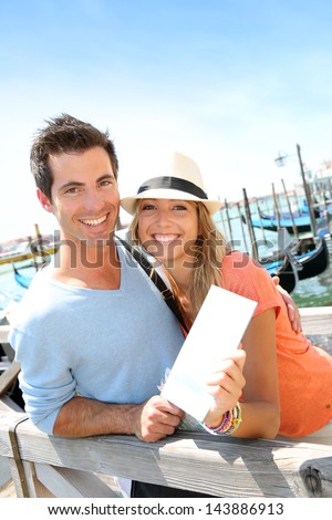 Cheerful couple in Venice showing tourist guide book
