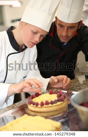 Pastry cook teaching student to make a cake