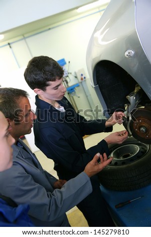 Instructor showing students how to repair car wheel