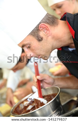 Chef in pastry looking at chocolate cake mixing