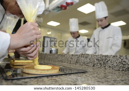 Closeup on pastry cook hand putting cream on cake