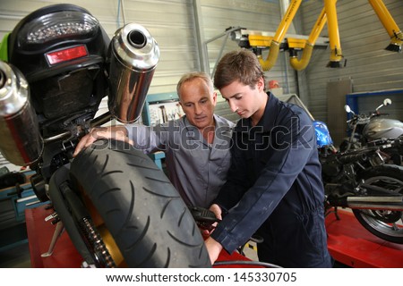 Teacher with students in mechanics working on bike Teacher with students in mechanics working on bike