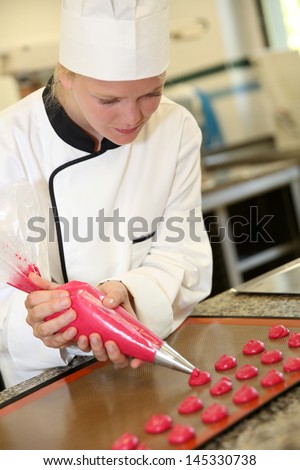 Pastry cook student making red cookies