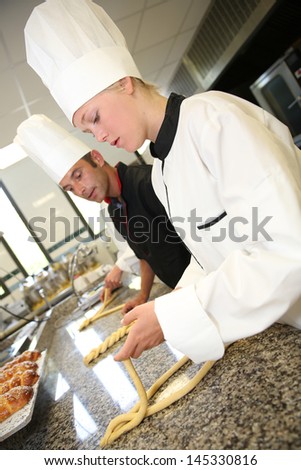 Baker with students in kitchen making pastries