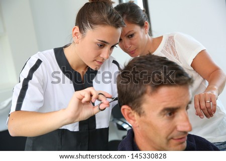 Student girl in hairdressing learning how to cut hair