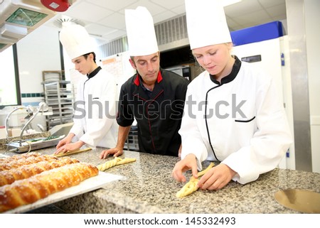 Baker with students in kitchen making pastries