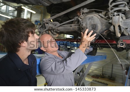 Mechanics teacher with student in car repairshop