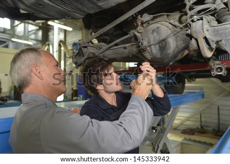 Mechanics teacher with student in car repairshop