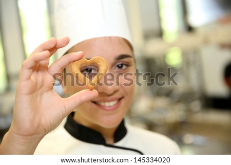 Portrait of young pastry cook holding cookie