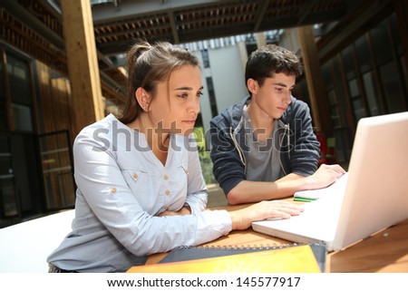 Teenagers working on laptop in school campus