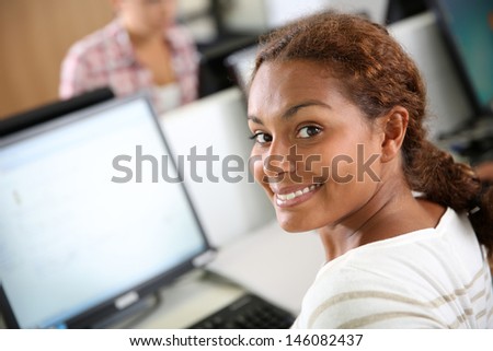 Smiling teenaged girl sitting in front of desktop