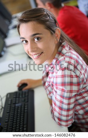Cheerful student girl sitting in front of desktop