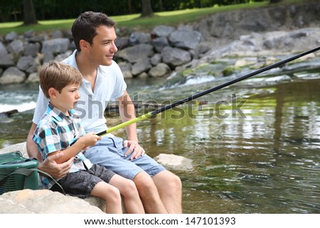 Father teaching son how to fish in river