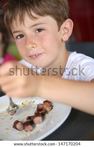 Portrait of young kid eating grilled food in summer