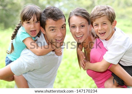 Portrait of happy parents holding kids on their back