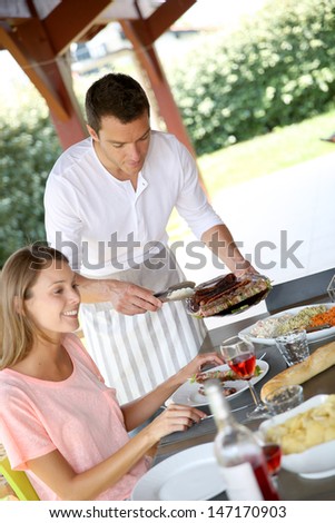 Man serving grilled food to family