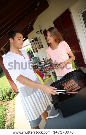 Couple cooking meat on grill at home