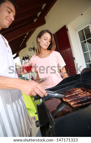 Couple cooking meat on grill at home