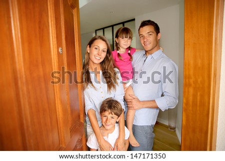 Family Standing On The Entrance Door Of New Home