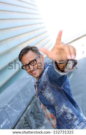 Cheerful trendy guy pointing at camera