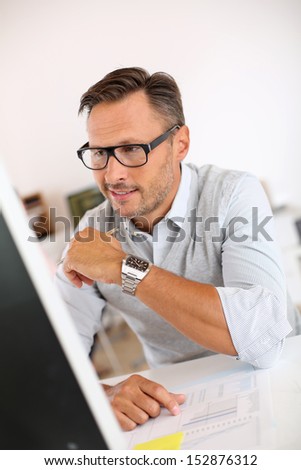 Cheerful man sitting in office and working on desktop