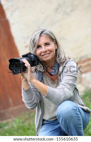 Portrait of mature woman shooting with photo camera