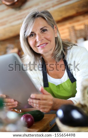 Senior woman cooking with help of recipe on tablet