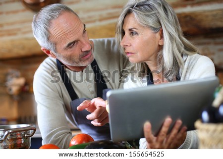 Senior couple in home kitchen looking at tablet