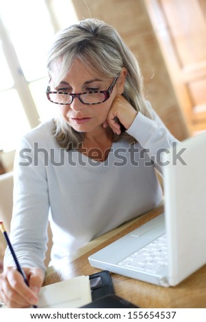 Senior woman at home figuring out income tax