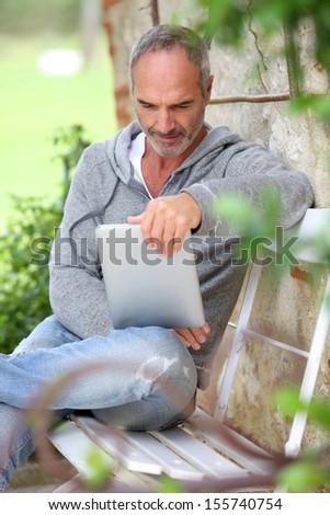 Mature man using tablet on a bench in countryside