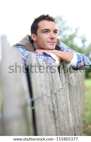 Man in countryside leaning on fence
