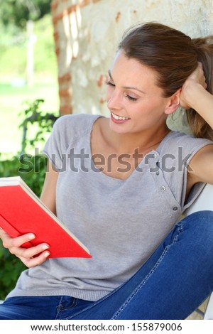 Portrait of beautiful girl reading book outside