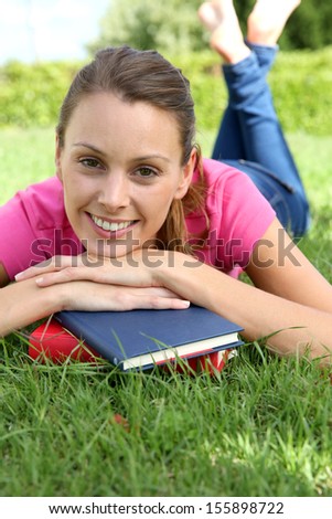 Smiling girl reading books laid in garden