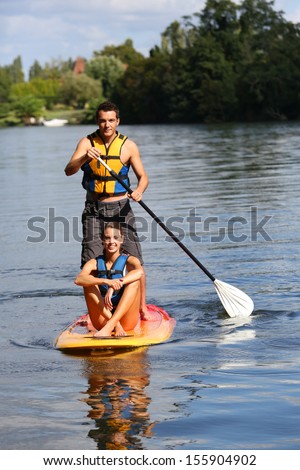 Couple riding stand-up-paddle on river