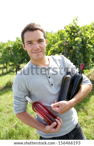 Young winegrower presenting wine bottles
