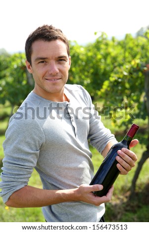 Young winegrower presenting wine bottles