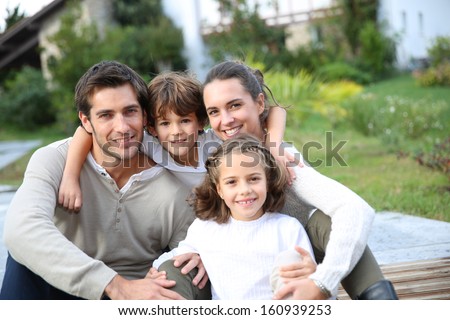 Parents With Kids Relaxing In Front Of Home