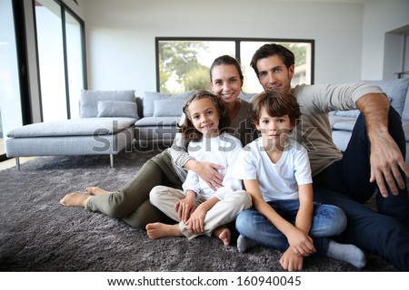 Happy Family Portrait At Home Sitting On Carpet