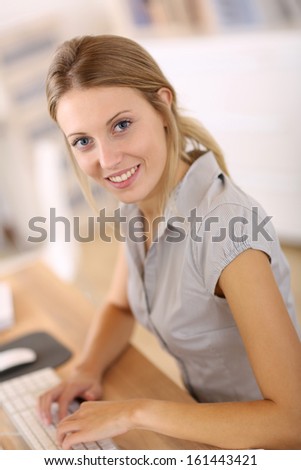 Beautiful blond girl working in office on desktop