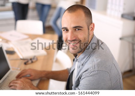 Smiling Young Man In Office Working On Laptop