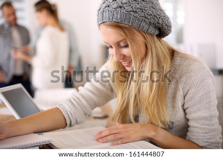 Blond student girl reading school books for examination