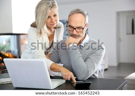Senior Couple At Home Using Internet On Laptop Computer