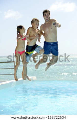 Man with kids jumping in swimming pool water
