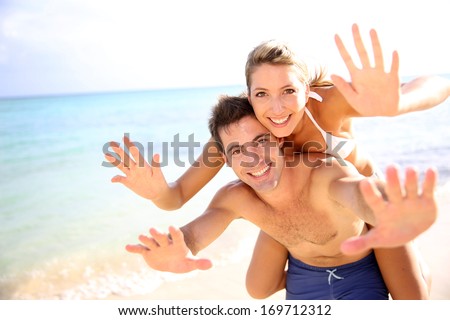 Man Giving Piggyback Ride To Girlfriend At The Beach
