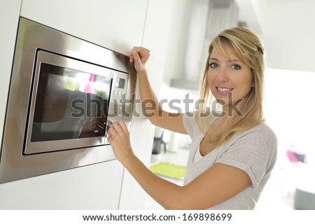 Woman at home using microwave oven