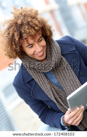Attractive man using digital tablet in town
